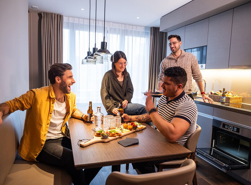 4 Gäste geniessen im Zimmer einen Apero