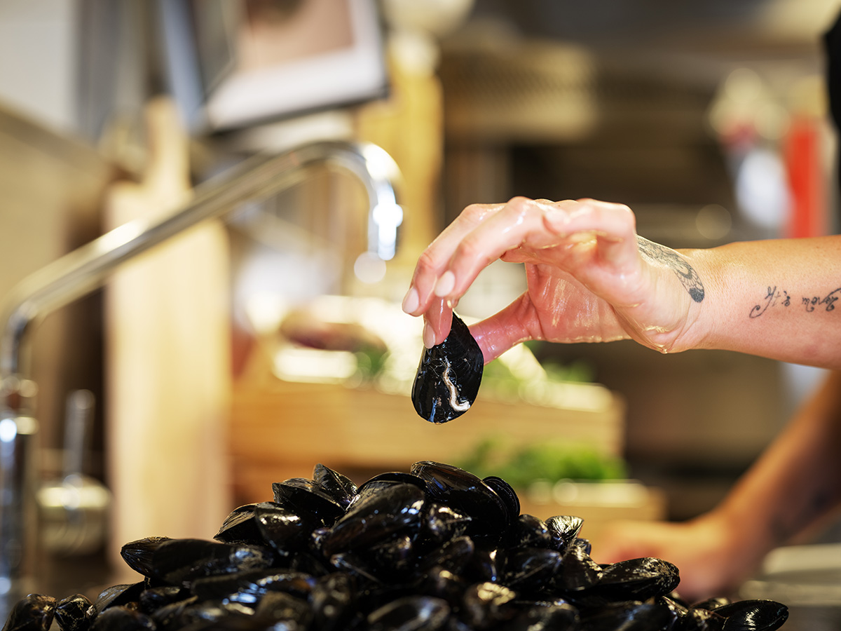Gros plan sur la cuisine : une cuisinière prépare des moules.