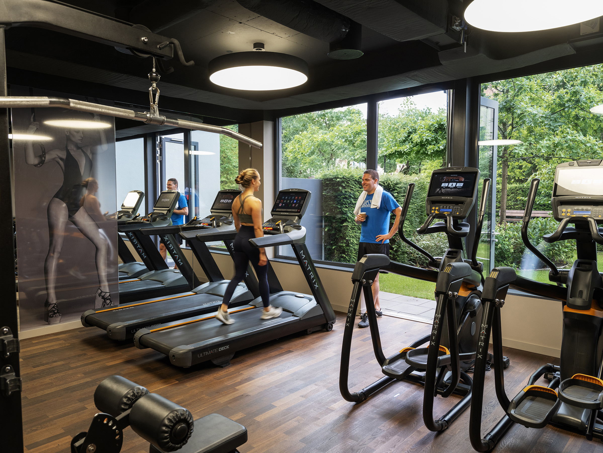 Gym with modern Matrix equipment and a view into the green garden at Acasa Suites Zurich Oerlikon